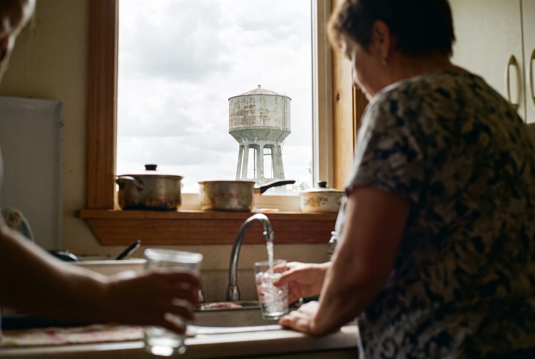 A kitchen sink with a glass being filled from the tap